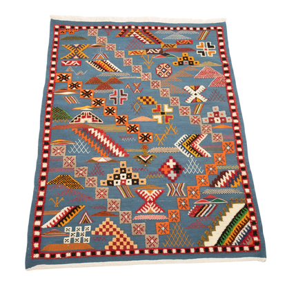 Full view of a handwoven Moroccan rug with a deep blue background and vibrant multicolored motifs.