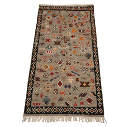 Full view of a handwoven Moroccan rug with a gray background